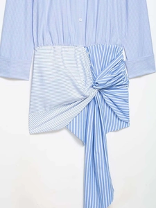 Detail of blue striped dress featuring twist waist design and asymmetric pleated hem