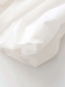 Detail of white poplin fabric with soft pleats and a minimalist smooth texture
