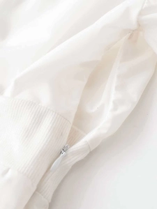 Close-up detail of white poplin mini dress showing zipper and ribbed knit sleeve cuffs
