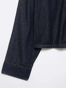 Detail of dark blue denim fabric showing orange contrast stitching and high-quality texture