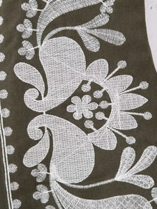 Gros plan détaillé d'une broderie florale blanche sur un tissu vert foncé de qualité