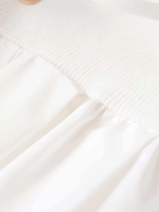 Detail of white dress showing ribbed elastic knit joined with pleated poplin fabric