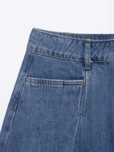 Detailed close-up of high-waisted denim skirt waistband showing stitching and belt loops