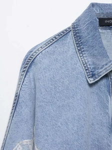 Detail view of denim jacket showing lace patchwork and shoulder seam craftsmanship