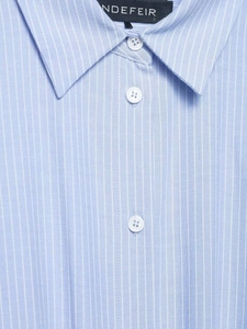 Close-up of the pointed collar and brand label on a blue and white striped cotton shirt