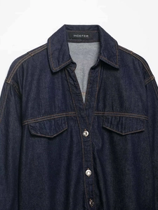 Detailed close-up of dark blue denim shirt collar with flap chest pockets and orange stitching