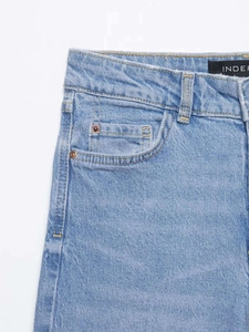 Détail du jean taille haute bleu clair montrant les poches et les rivets métalliques