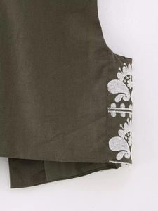Détail de broderie florale blanche sur tissu en coton de gilet vert armée foncé