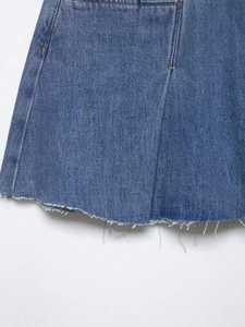 Close-up of raw hem details and yellow stitching on blue denim skirt fabric