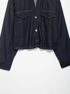 Detail of dark blue denim jacket with contrast stitching and silver metal buttons