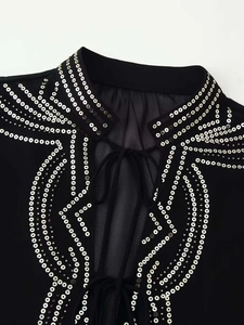 Detail of black sheer shirt featuring silver sequins and lace-up V-neckline collar