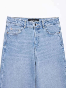 Détails du jean bleu clair à taille haute montrant le bouton métallique et les poches classiques