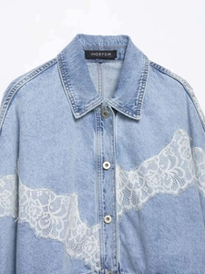 Close-up of white floral lace patchwork on light blue denim jacket with metal buttons