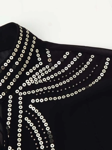 Close-up of black blouse featuring silver sequins and metal studs in geometric patterns