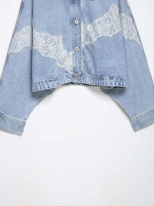 Detail of light blue denim jacket with white floral lace trim and frayed hemline