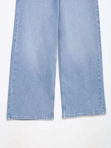 Gros plan sur un jean large bleu clair montrant la texture délavée et les finitions soignées