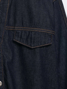 Detail of dark blue denim fabric with contrast amber stitching and metal button