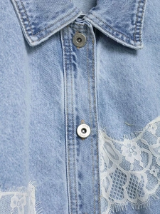 Close-up of light blue denim jacket featuring intricate white lace trim and metal buttons