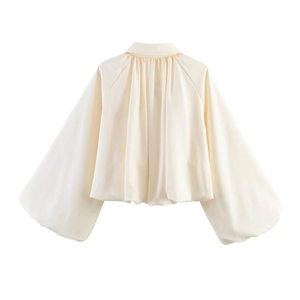 Detail of minimalist cream blouse featuring puffy lantern sleeves and elegant back pleats