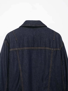 Detail view of the back of a dark blue denim jacket with contrast stitching and seams