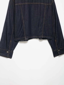 Detail view of dark blue denim jacket featuring contrast stitching and metallic buttons