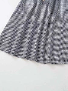 Detailed view of black and white gingham skirt fabric with pleated A-line hem texture