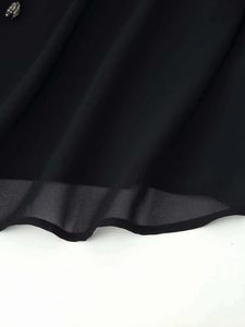 Close-up of black sheer chiffon fabric with decorative rivet button and fine hem details