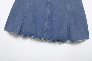 Detail of blue denim skirt hem with frayed edges and double vertical stitching accents