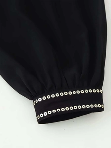 Detail of black chiffon sleeve cuff featuring two rows of golden sequin embellishments