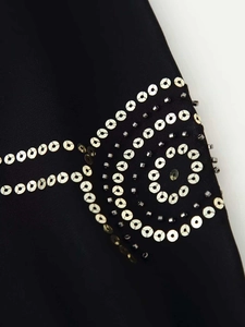 Close-up of intricate silver rivets and beads on black sheer fabric for women
