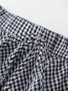 Close-up of black and white gingham skirt featuring elastic waist and tie-up detail