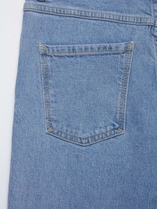 Gros plan sur la poche arrière du jean bleu clair avec détails de doubles surpiqûres jaunes