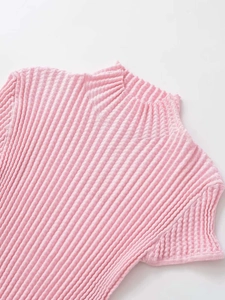 Dettaglio top in maglia rosa con collo a lupetto, texture plissettata e bordi ondulati