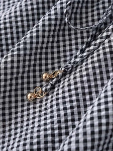 Detail of black and white gingham skirt featuring drawstring and gold metallic ball ends