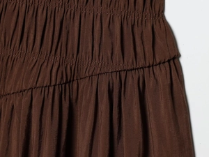 Detail view of brown smocked waist with layered ruffles on an elegant midi dress