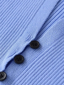 Detail of sky blue knit cardigan featuring vertical ribbed texture and black buttons