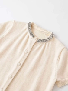 Detail of knit cardigan collar featuring sparkling rhinestones and matching buttons