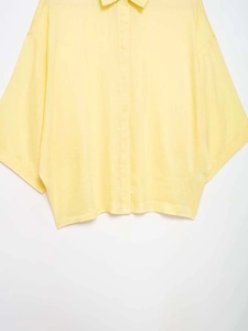 Detailed view of light yellow linen-textured short-sleeve shirt with button-down collar