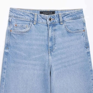 Jean en denim délavé bleu clair à taille haute et jambe large avec cinq poches classiques