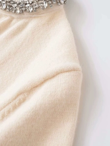 Detailed close-up of crystal rhinestones on off-white knit cardigan neckline