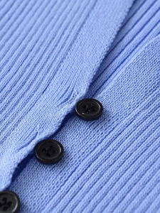 Detailed view of light blue ribbed knit cardigan with three black matte buttons