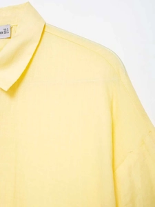 Detailed close-up of light yellow shirt collar and fabric texture with size label