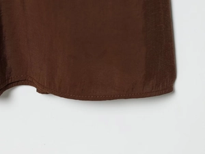 Detail of the dark brown midi dress featuring a curved hemline and fine stitching