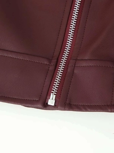 Détail de la fermeture éclair en métal argenté sur la veste en similicuir bordeaux