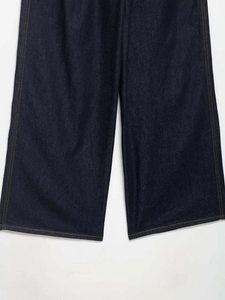Detail of dark blue wide-leg denim jeans with orange contrast stitching and twill texture