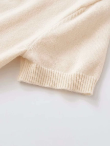 Close-up of cream short sleeve knit cardigan with ribbed cuffs and soft wool texture