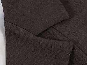 Detail of premium brown woven fabric with precise stitching on casual blazer sleeve