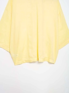 Detail of light yellow knit cotton shirt hem and sleeve with oversized fit texture