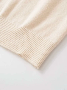 Detailed close-up of premium beige knit cardigan featuring ribbed hem and soft wool texture