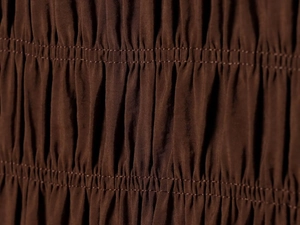 Detail of dark brown shirred fabric with elastic parallel stitching and cotton texture
